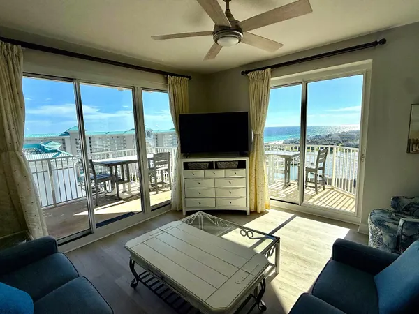 a living room with furniture a flat screen tv and floor to ceiling window