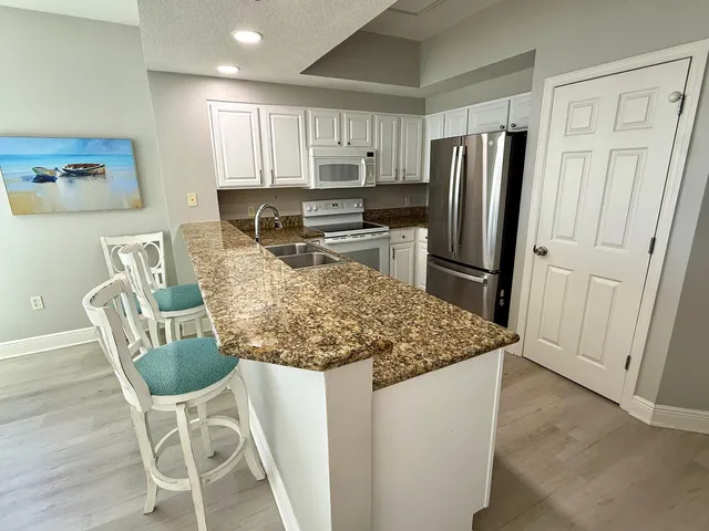 a kitchen with stainless steel appliances granite countertop a refrigerator and a stove top oven