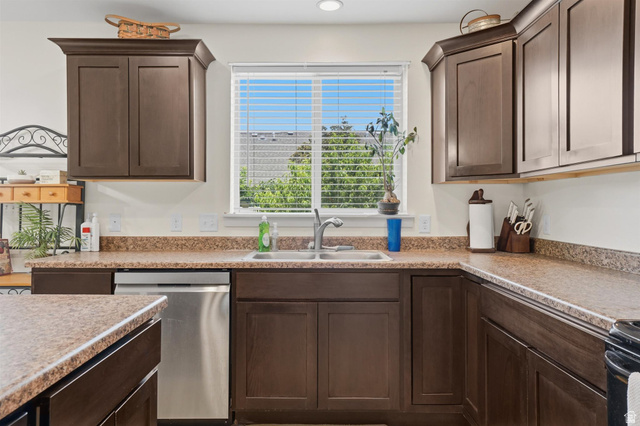 592 West 650 South Springville, UT 84663 - Photo 13 of 33 Kitchen featuring dark wood cabinetry, a stainless steel sink, speckled laminate countertops, and a built-in stainless steel dishwasher