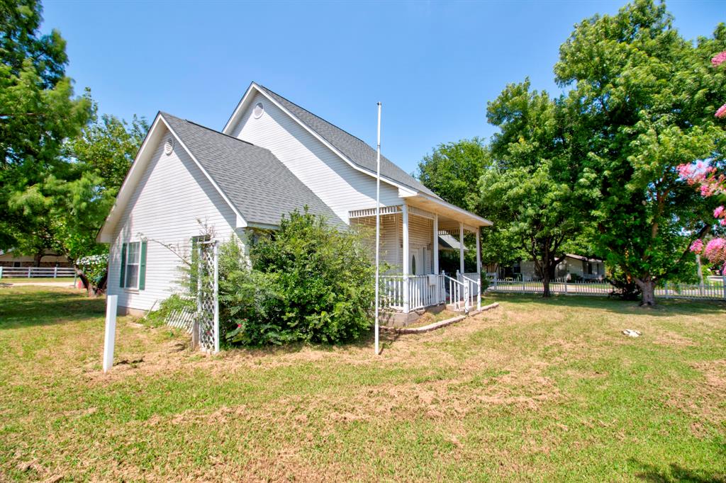 503 Sherman Street Tioga, TX 76271 - Photo 4 of 13 White siding exterior with a dark shingle roof and a covered front porch featuring white railings