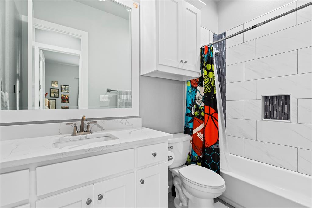 1024 Henry Way Springtown, TX 76082 - Photo 22 of 29 Bathroom featuring a white vanity with an integrated sink, brushed nickel faucet, large framed mirror, and white subway tile shower surround with a mosaic tile niche