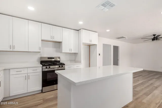 a kitchen with stainless steel appliances a white stove top oven and white cabinets
