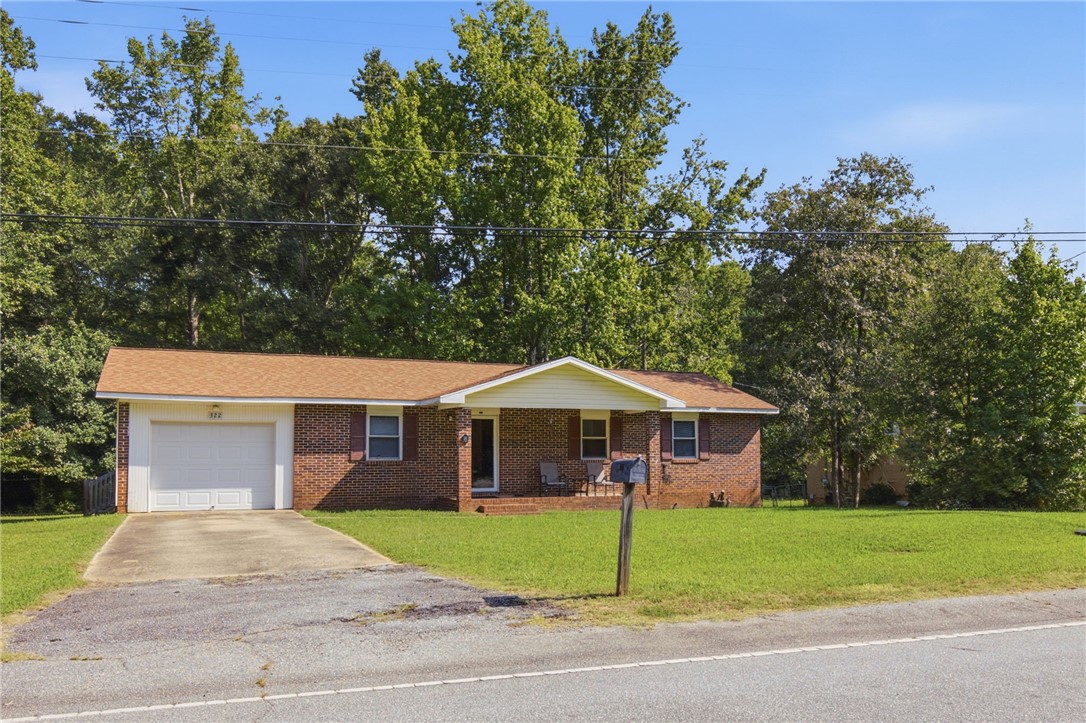 322 Tribble Street Honea Path, SC 29654 - Photo 4 of 35 Classic brick architecture defines this charming ranch-style residence nestled against a lush backdrop of mature trees.