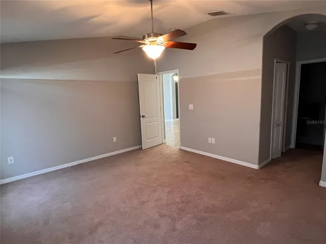 a view of an empty room with a chandelier fan