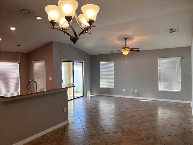 a view of a livingroom with a large window chandelier fan and wooden floor