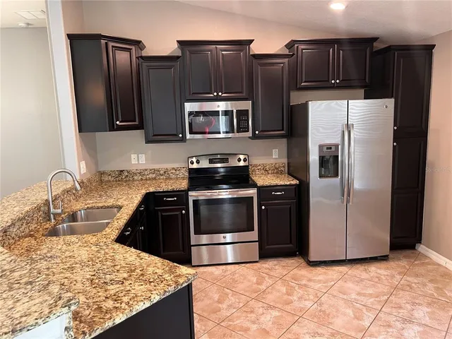 a kitchen with granite countertop a refrigerator and a sink