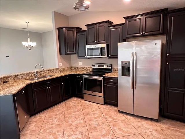 a kitchen with stainless steel appliances granite countertop a refrigerator and a sink