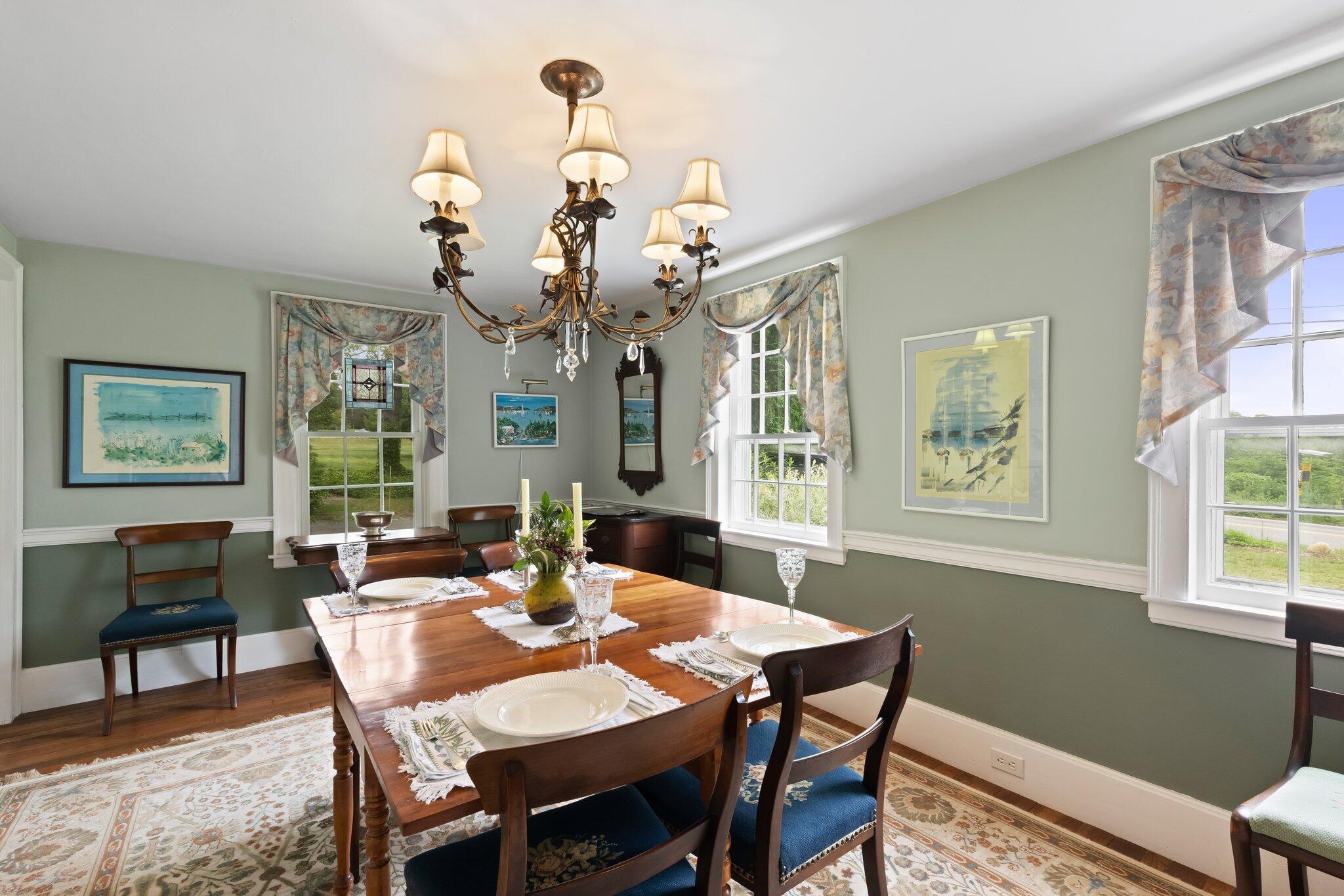 152 Monument Road Orleans, MA 02653 - Photo 3 of 40 a dining room with wooden floor a chandelier a wooden table and chairs