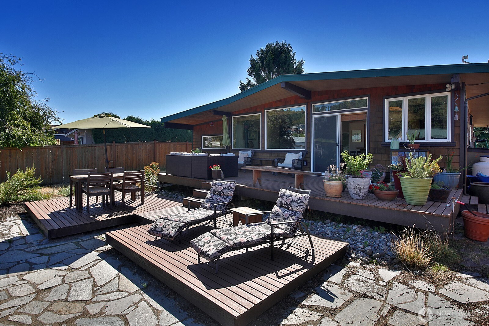 8121 Sandy Hook Terrace Clinton, WA 98236 - Photo 27 of 40 a view of a patio with couches table and chairs under an umbrella with a patio