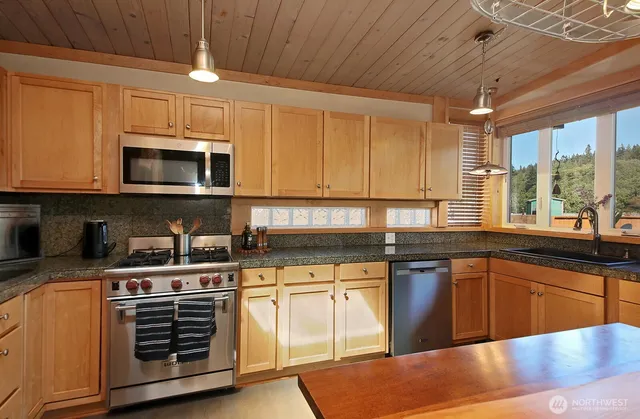 a kitchen with stainless steel appliances granite countertop a stove sink and microwave