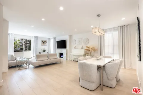 a living room with furniture kitchen view and a large window