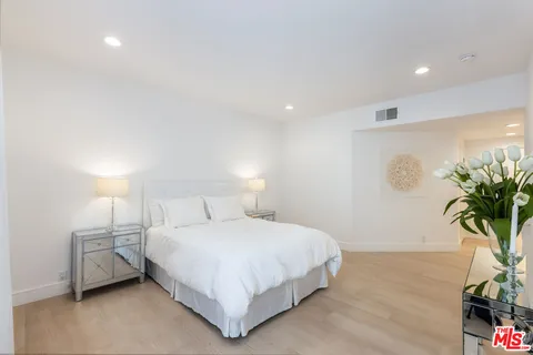 a bedroom with a bed lamp and a potted plant