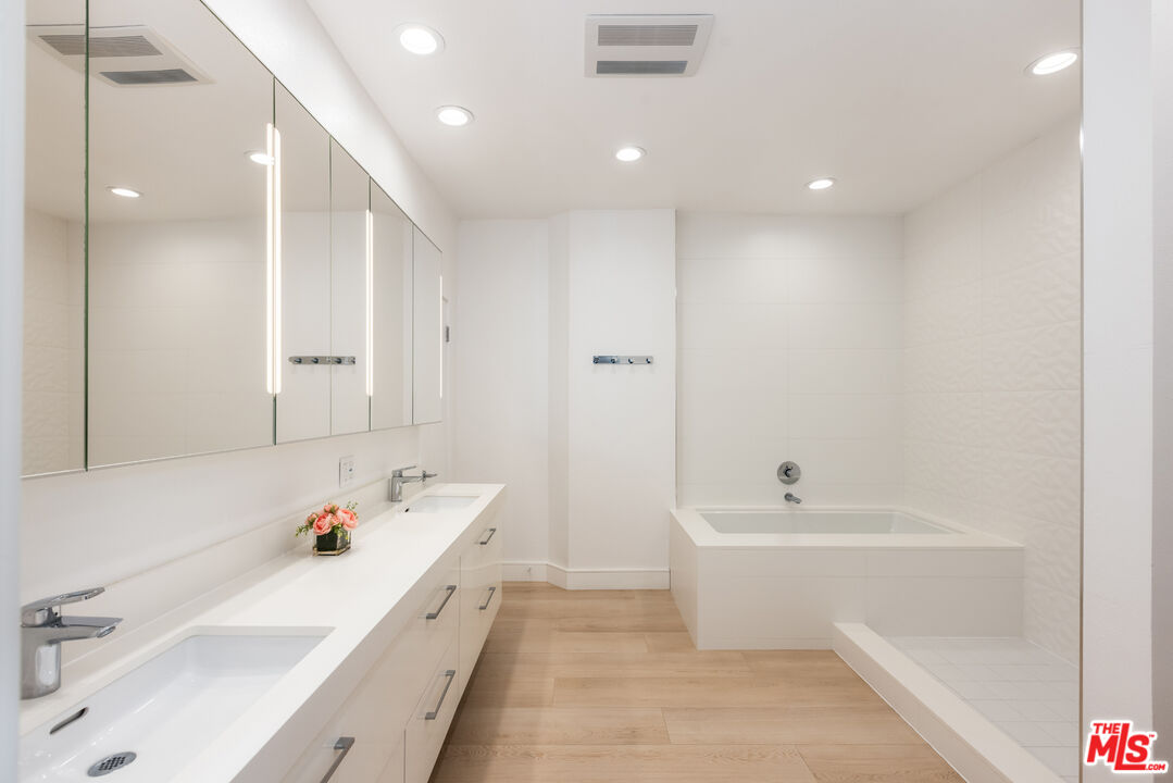 1164 Wellesley Avenue, Unit 101 Los Angeles, CA 90049 - Photo 13 of 25 a bathroom with a tub a sink and a large mirror