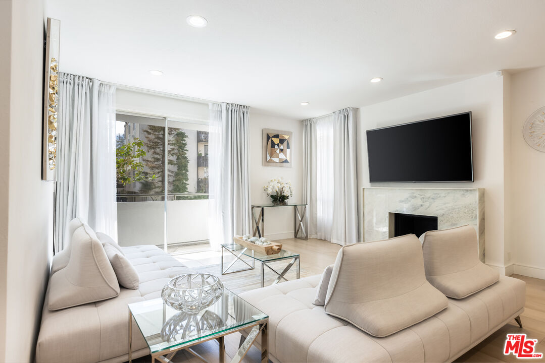 1164 Wellesley Avenue, Unit 101 Los Angeles, CA 90049 - Photo 6 of 25 a living room with furniture a fireplace and a flat screen tv