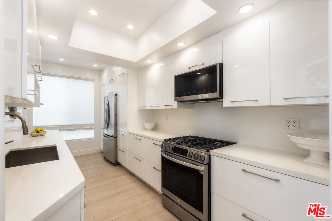 1164 Wellesley Avenue, Unit 101 Los Angeles, CA 90049 - Photo 8 of 25 a kitchen that has a lot of white cabinets and stainless steel appliances