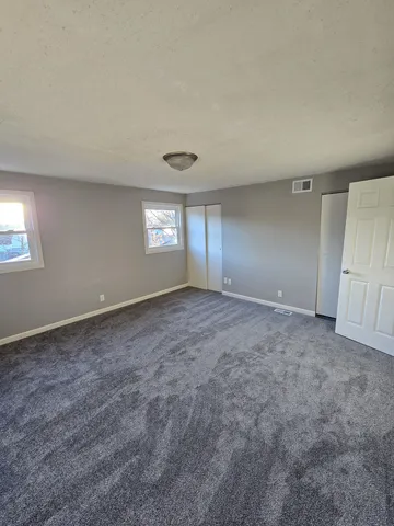 a view of an empty room with window and closet area