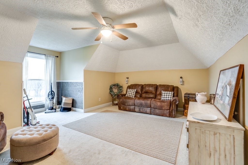 4121 New Milford Road Rootstown, OH 44272 - Photo 31 of 50 Living room featuring ceiling fan, carpet, a textured ceiling, vaulted ceiling, and baseboards