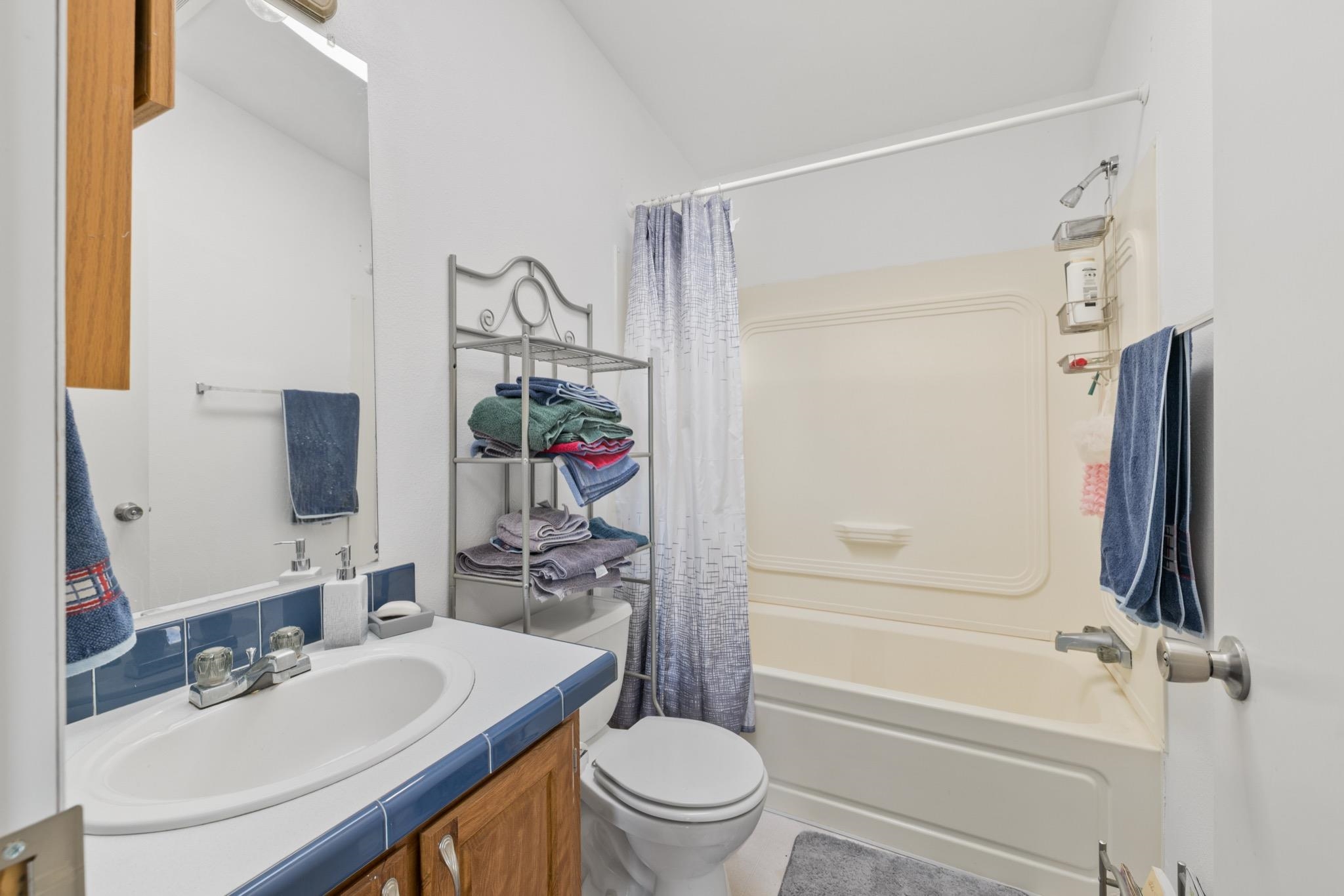 790 Cemetery Road Lee Vining, CA 93541 - Photo 28 of 39 White vanity with a drop-in sink, blue tile countertop, and wood-finish cabinetry