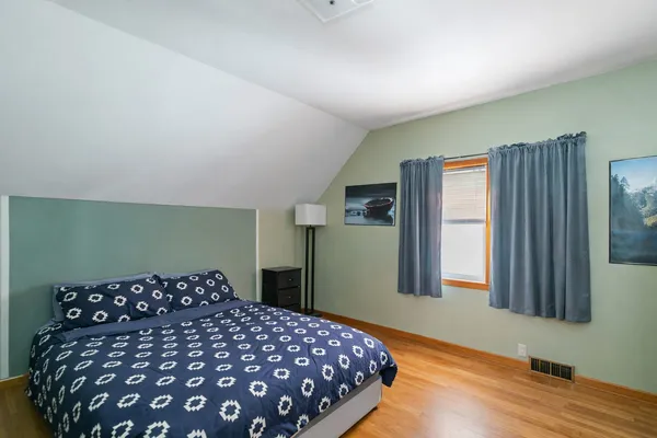 a bedroom with a large bed and wooden floor