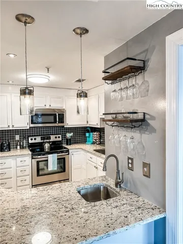 a kitchen with stainless steel appliances granite countertop a sink a stove and a wooden floor