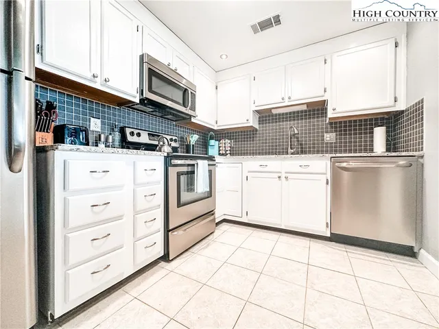 a kitchen with stainless steel appliances cabinets and a window