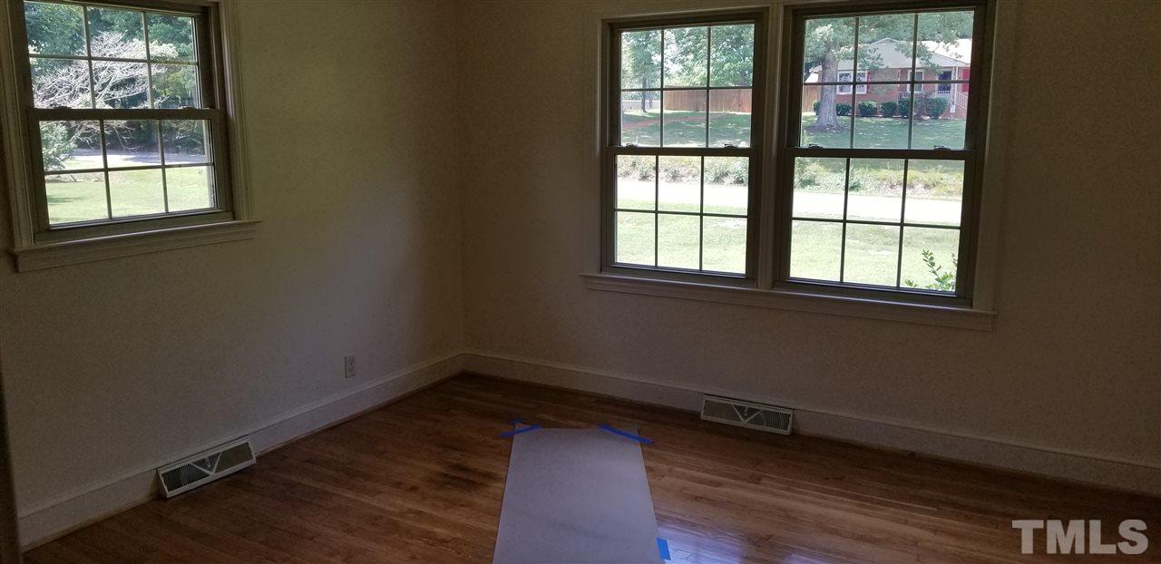 181 Henderson Road Roxboro, NC 27573 - Photo 8 of 14 an empty room with wooden floor and windows