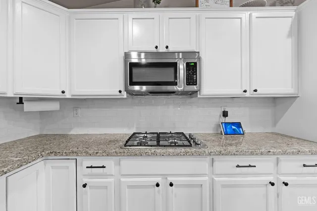 a kitchen with granite countertop white cabinets and a white stove