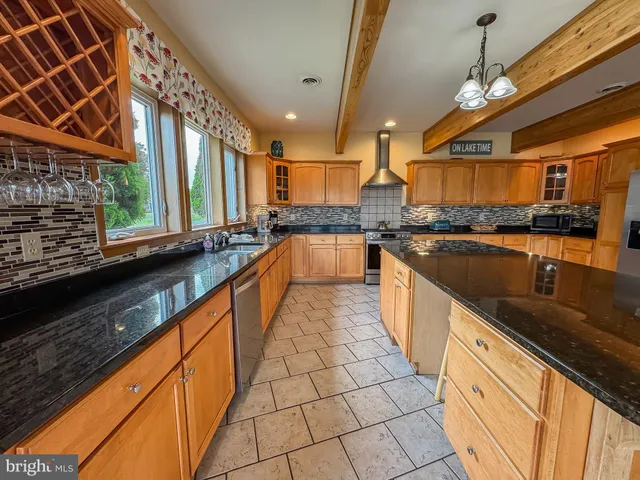 a large kitchen with granite countertop a sink a counter top space and stainless steel appliances
