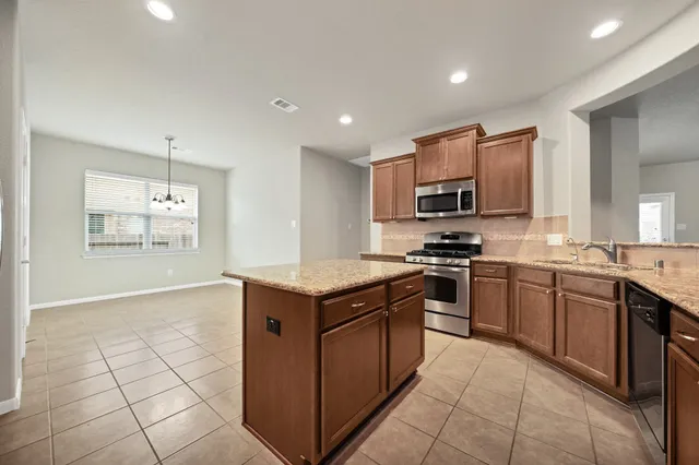 a kitchen with stainless steel appliances granite countertop a stove top oven a sink dishwasher and a refrigerator