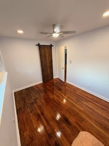 an empty room with wooden floor ceiling fan and windows