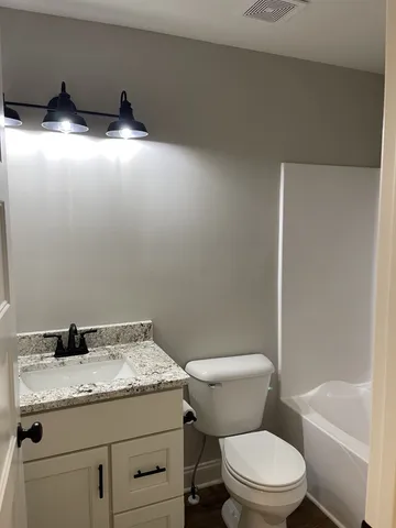 a bathroom with a granite countertop toilet a sink and bathtub