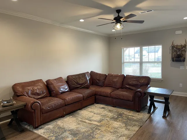 a living room with furniture ceiling fan and a window