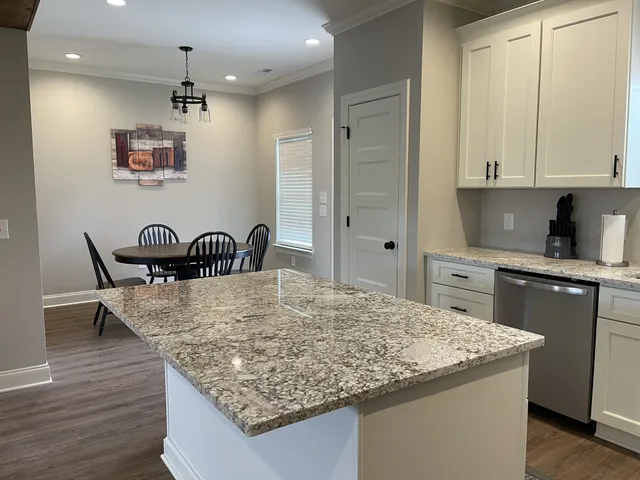 a kitchen with granite countertop a table chairs and wooden floor
