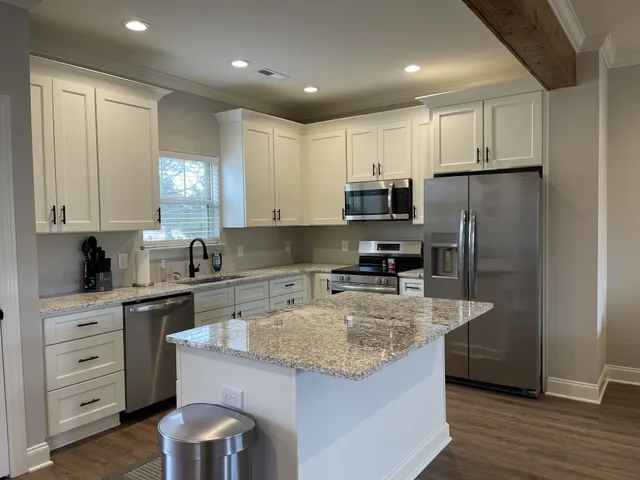 a kitchen with kitchen island granite countertop a sink a counter space appliances and cabinets