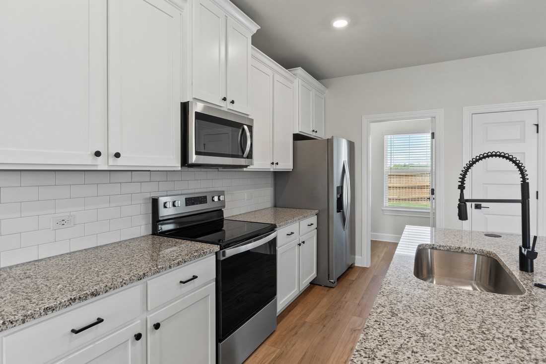 9517 Balmy Lane Manor, TX 78653 - Photo 4 of 17 a kitchen with granite countertop a sink stainless steel appliances and cabinets