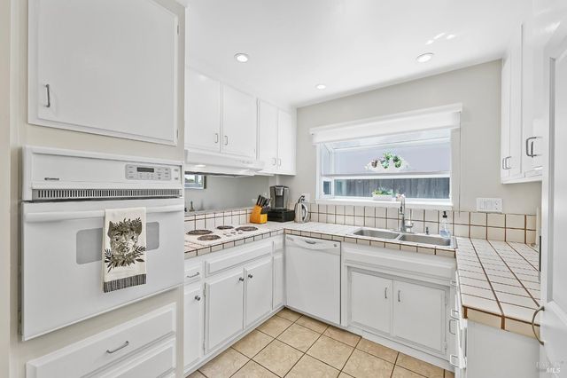 a kitchen with a sink white cabinets and white appliances