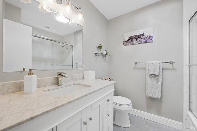 a bathroom with a granite countertop sink a toilet and a shower