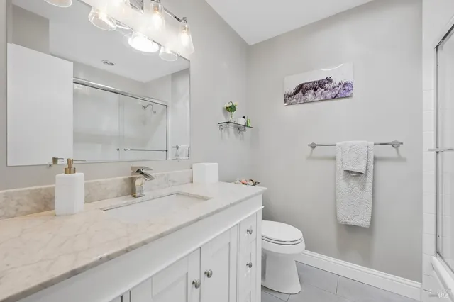 a bathroom with a granite countertop sink a toilet and a shower