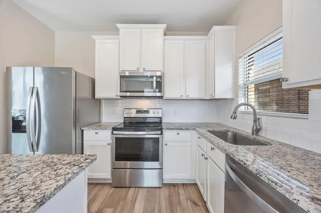 a kitchen with kitchen island granite countertop wooden floor and white cabinets
