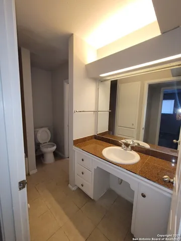 a bathroom with a granite countertop sink a toilet a mirror and shower