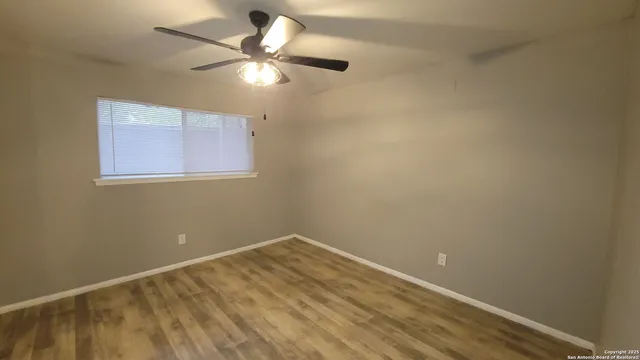 an empty room with a window and a fan