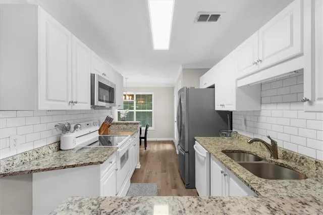 a kitchen with granite countertop a sink stainless steel appliances and cabinets