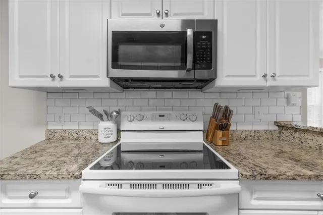 a kitchen with white cabinets and appliances