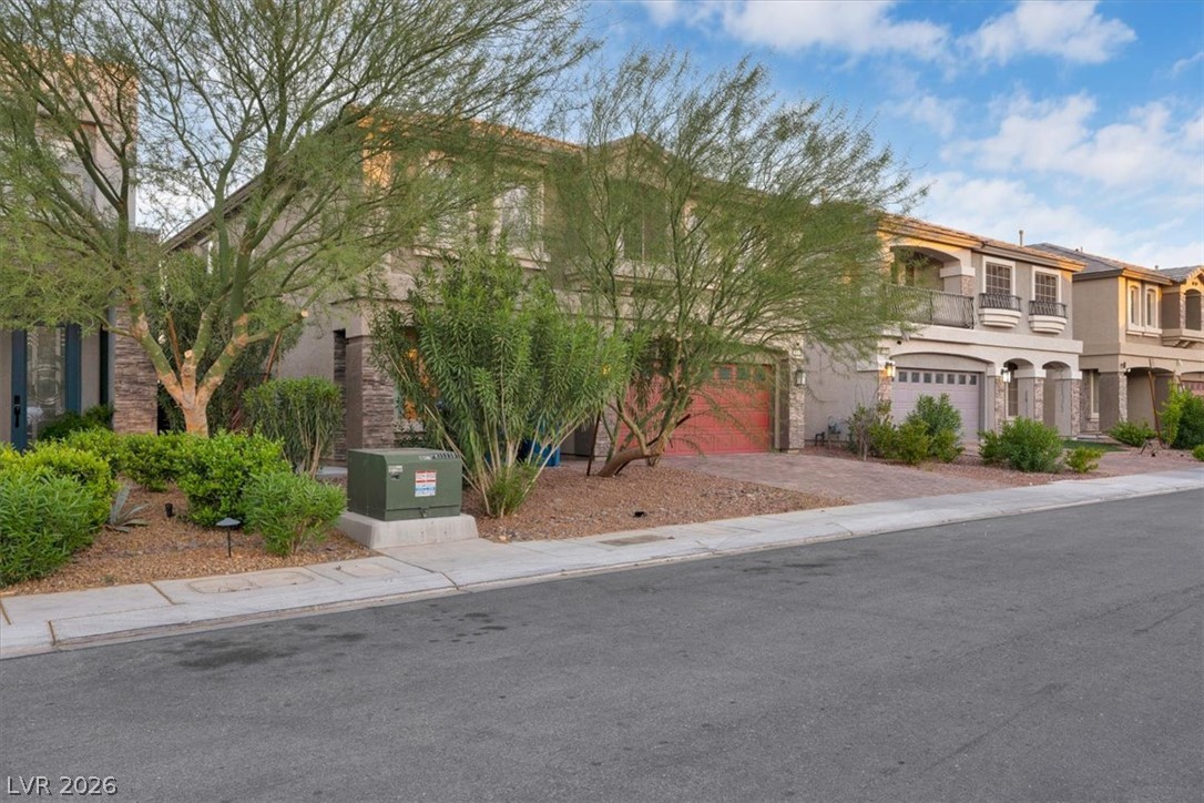 8046 Noble Ridge Street Las Vegas, NV 89139 - Photo 32 of 34 A contemporary residence boasts a bold red garage door and decorative stone accents, framed by verdant landscaping.