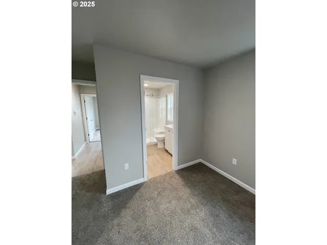 a view of an empty room with closet and windows