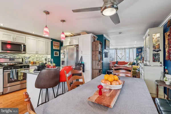 a kitchen with stainless steel appliances granite countertop a stove top oven a sink dishwasher and a dining table with chairs