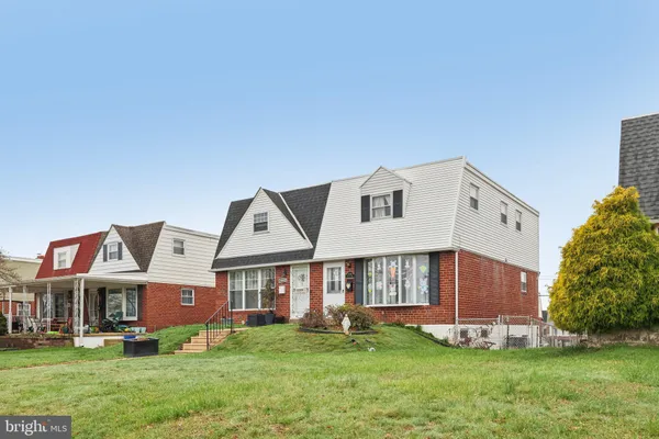 a view of a white house with a big yard and large trees