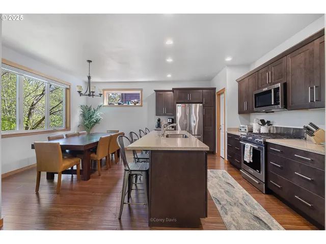 a kitchen with stainless steel appliances granite countertop a stove a refrigerator a kitchen island a dining table and chairs