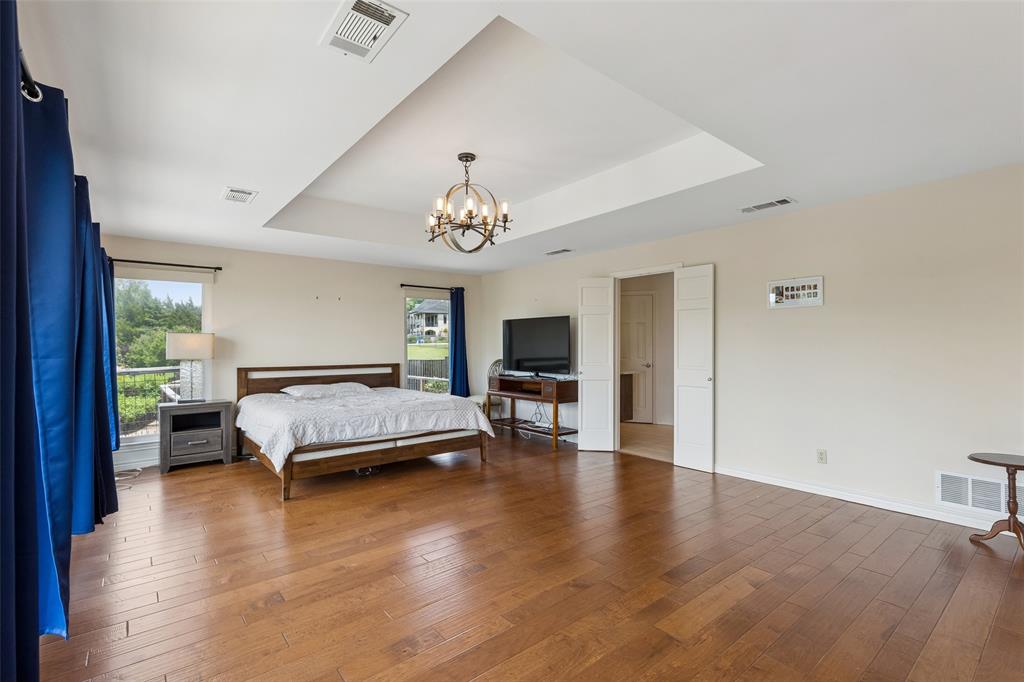 4 Eastshore Road Heath, TX 75032 - Photo 27 of 37 a spacious bedroom with a bed and a chandelier