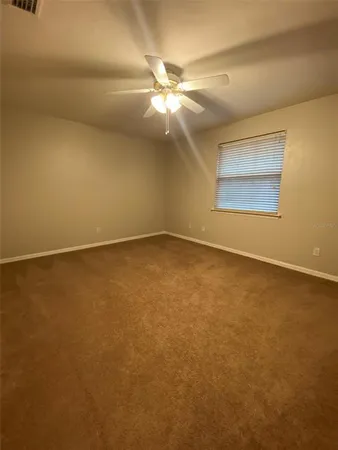 an empty room with a ceiling fan and a window